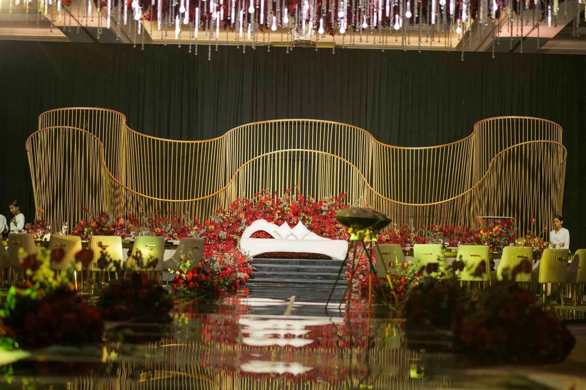 Gold wire-work stage with red roses at a wedding reception we produced